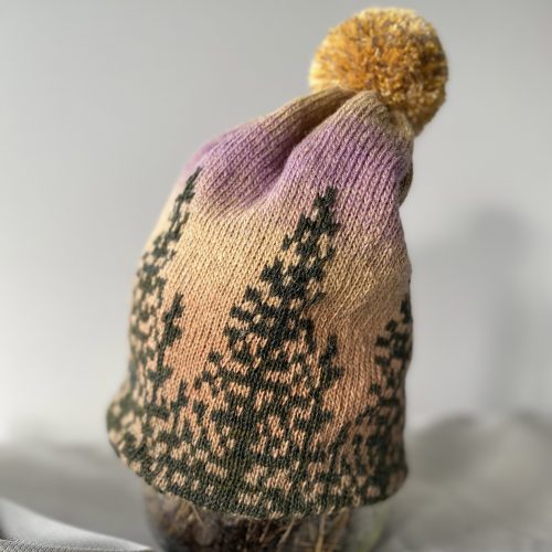Hand knitted wool hat with pine trees in the sunset, colored in yellow-and-lillic tones
